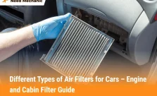 Mechanic holding a dirty cabin air filter while replacing it inside a car, showing example of different types of air filters for cars.
