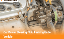 Close-up of car engine showing power steering fluid leaking from pump and hoses under the vehicle